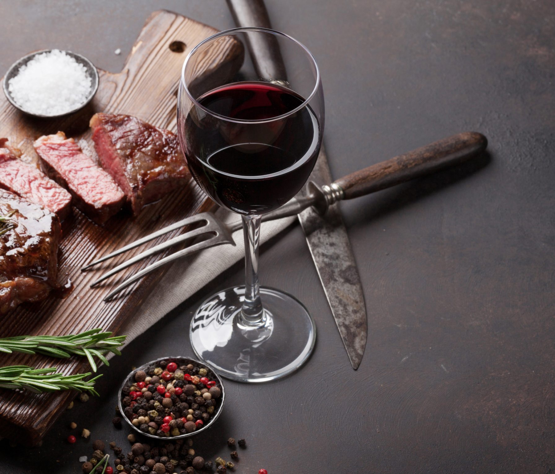 Grilled ribeye beef steak with red wine, herbs and spices on stone table